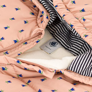 Pink quilt with floral patterns and a striped section, featuring a brand label.