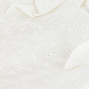 Close-up of a white lace garment with a scalloped edge.
