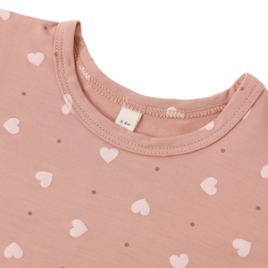 Close-up of a pink garment with heart patterns and a visible brand tag.