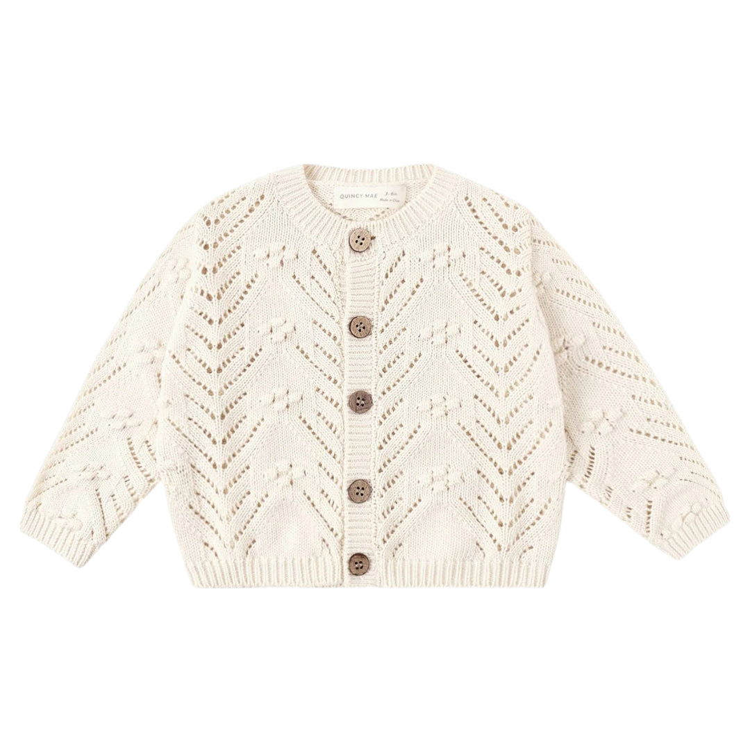 Cream-colored knitted cardigan with button details on a white background
