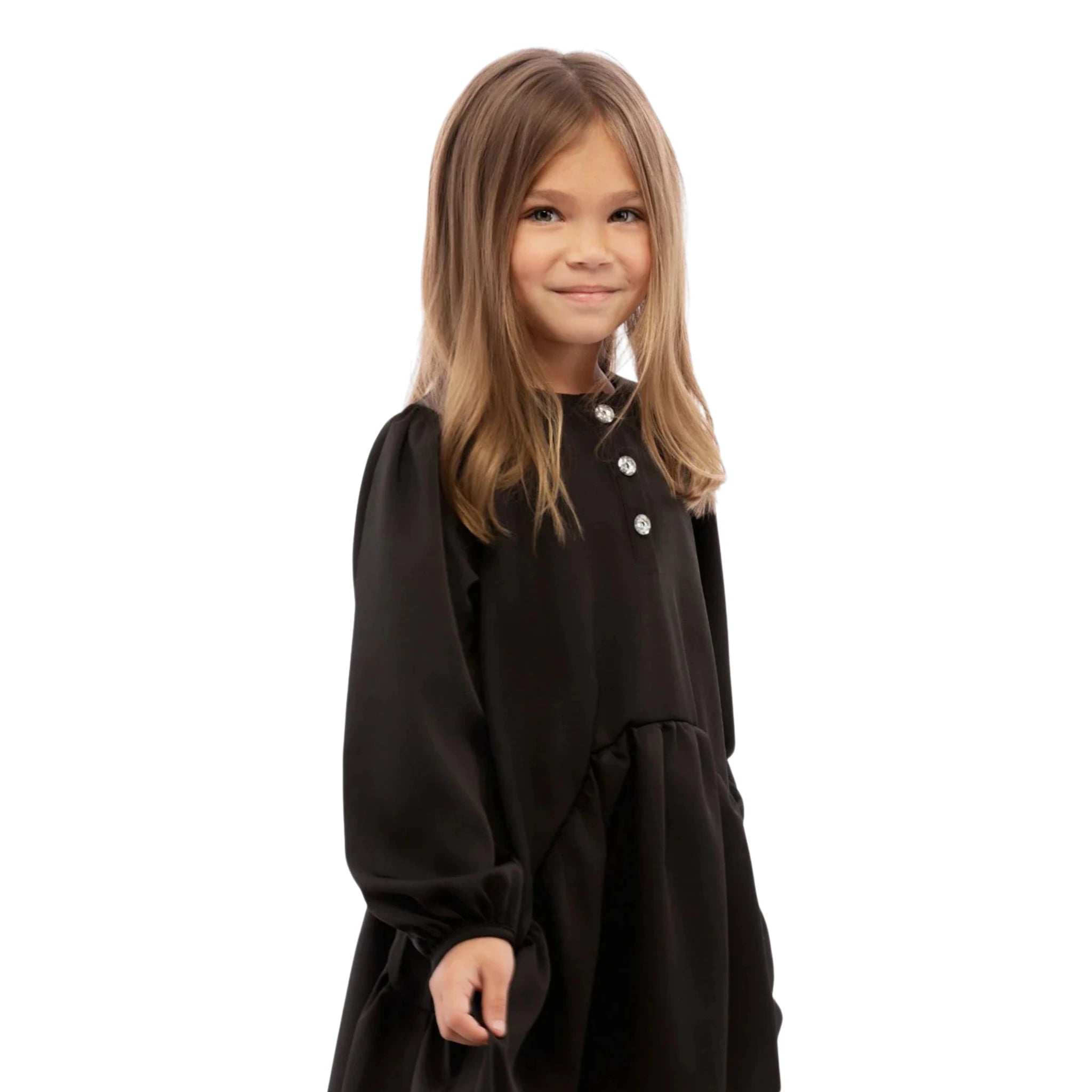 Young girl wearing a black dress with white buttons on a white background