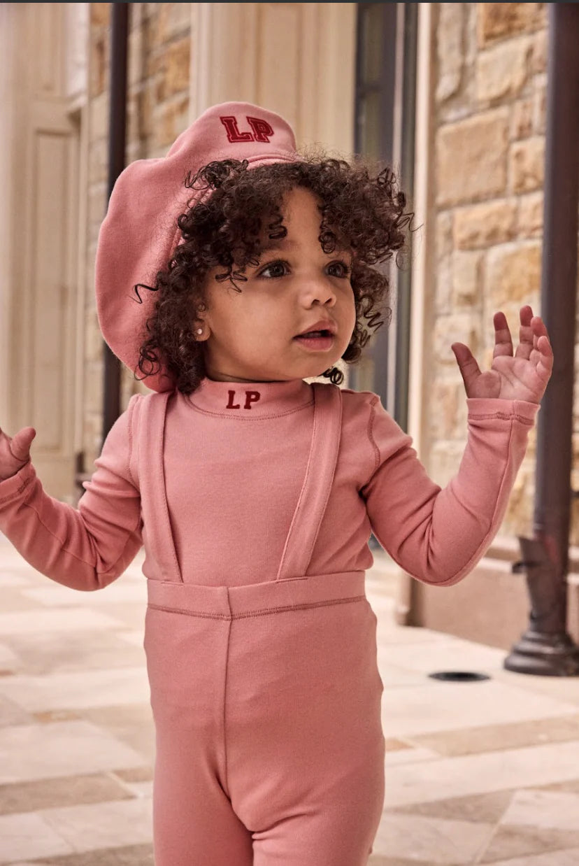 Child wearing a pink outfit with 'LP' logo outdoors.