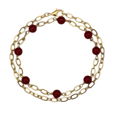 Double-layered gold chain bracelet with red beads on a white background