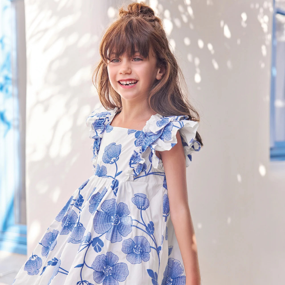 Young girl wearing a blue floral dress against a light background
