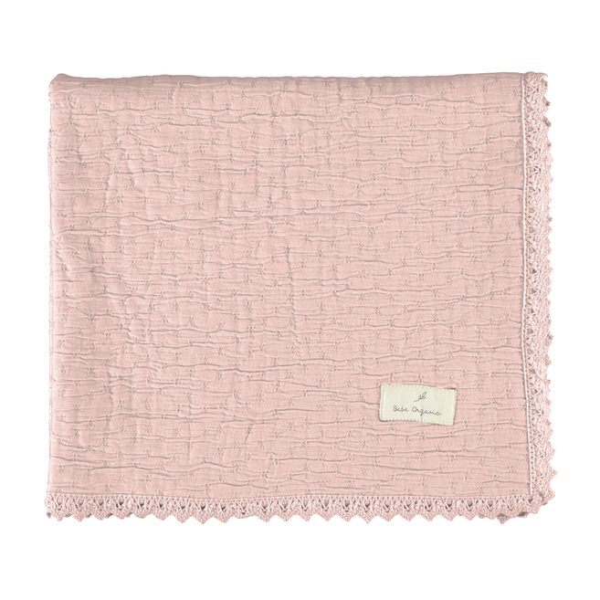 Pink textured blanket with a brand label on a white background