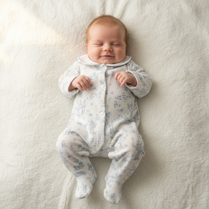 Baby in a floral onesie lying on a soft, light-colored surface