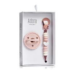 Adora baby gift set in a white box, featuring a pale pink silicone pacifier and a rose gold and cream beaded pacifier clip.