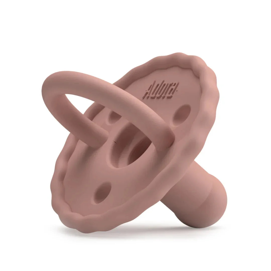 Pink silicone baby teether on a white background