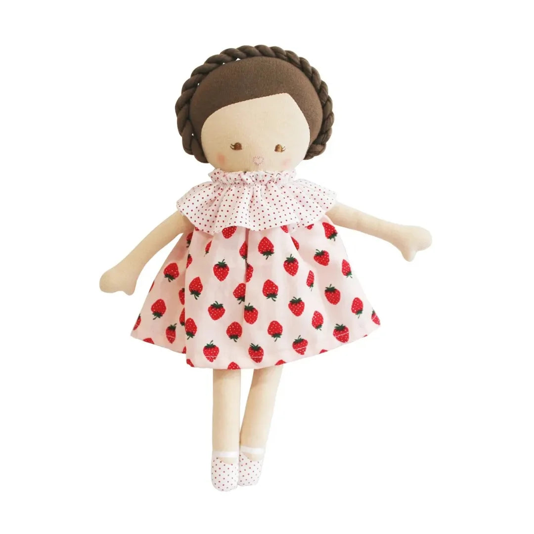 A handmade fabric doll with a brown braided hair bun, wearing a pink polka-dot ruffled collar and a pink skirt patterned with red strawberries, set against a plain white background.