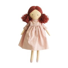 A handmade wooden doll with red yarn hair styled in pigtails, wearing a dusty pink linen dress, shown against a plain white background.