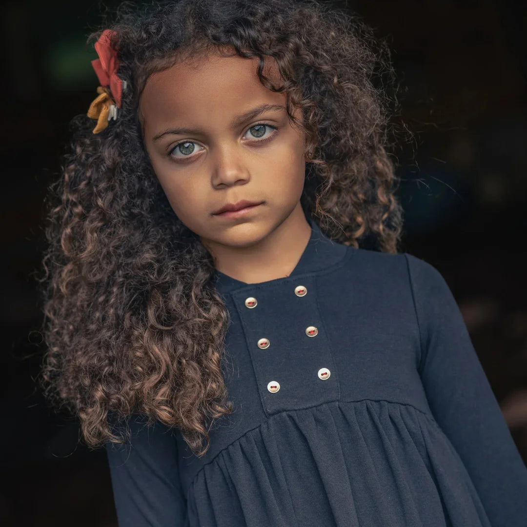 A child wearing the Ann of Nan black maxi robe happily during an outdoor seasonal outing.