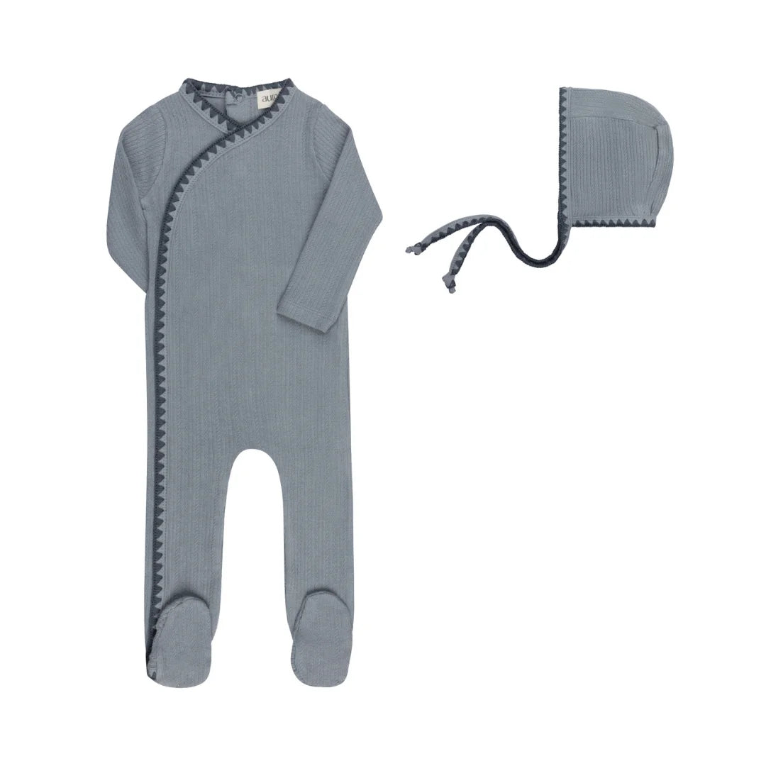 A front view of the Aurora whipstitch footie and matching bonnet set in blue.