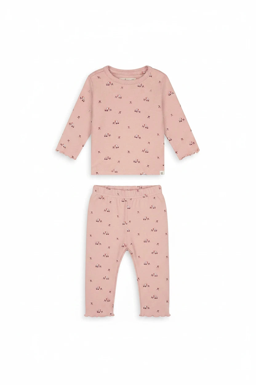 A pink long-sleeve baby top with a small all-over pattern of tiny red bows and white star-shaped embellishments, displayed flat against a solid white background.