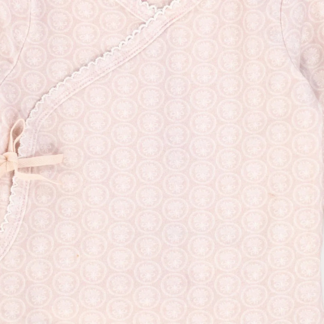 A high-resolution close-up of the delicate floral print and soft organic fabric texture.