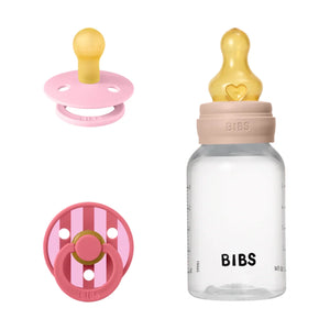 BIBS pacifier and bottle set with pink and gold accents on a white background