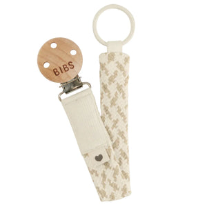 Nursing clip with wooden pacifier clip and textured strap on a white background