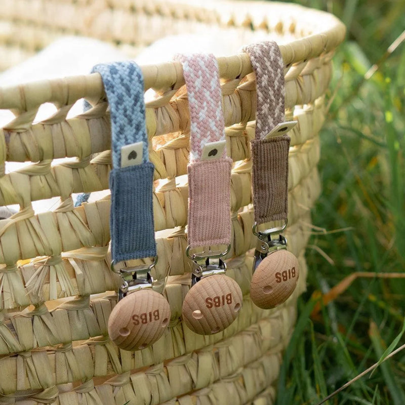 A breathtaking BIBS Braided Pacifier Clip showcasing its immaculate organic cotton weave and timeless wooden clasp.