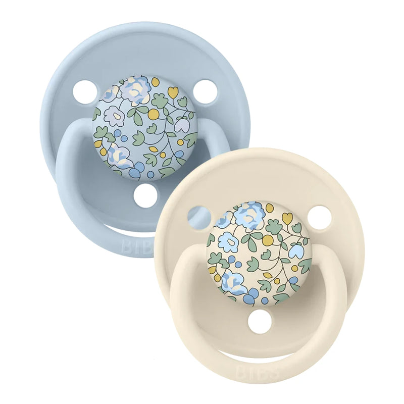 Two floral-patterned baby pacifiers, one blue and one beige, on a white background.
