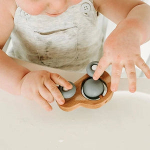 Child playing with a wooden fidget toy on a white surface