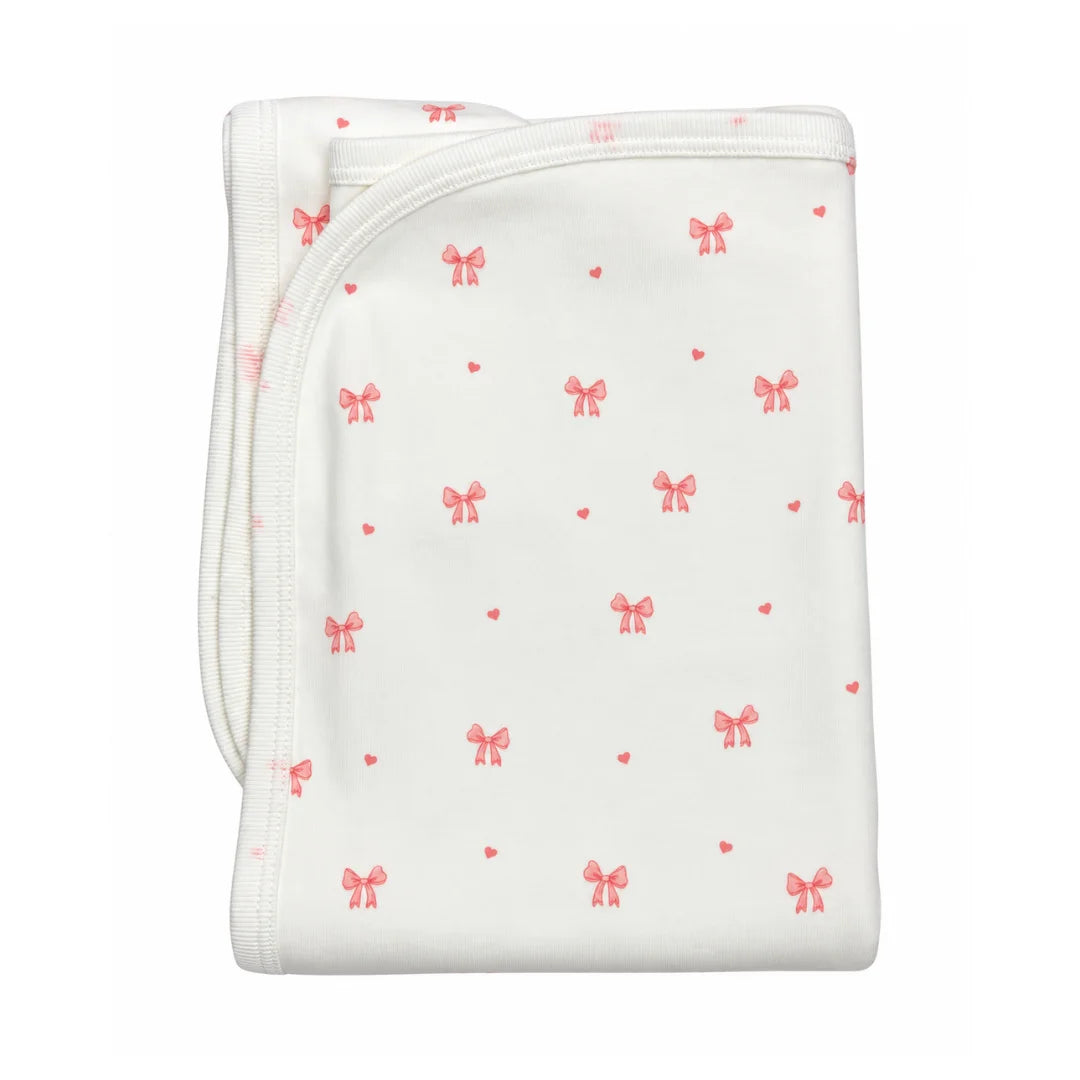 A flat-lay view of the Coton Pompom bows knit blanket in ivory.