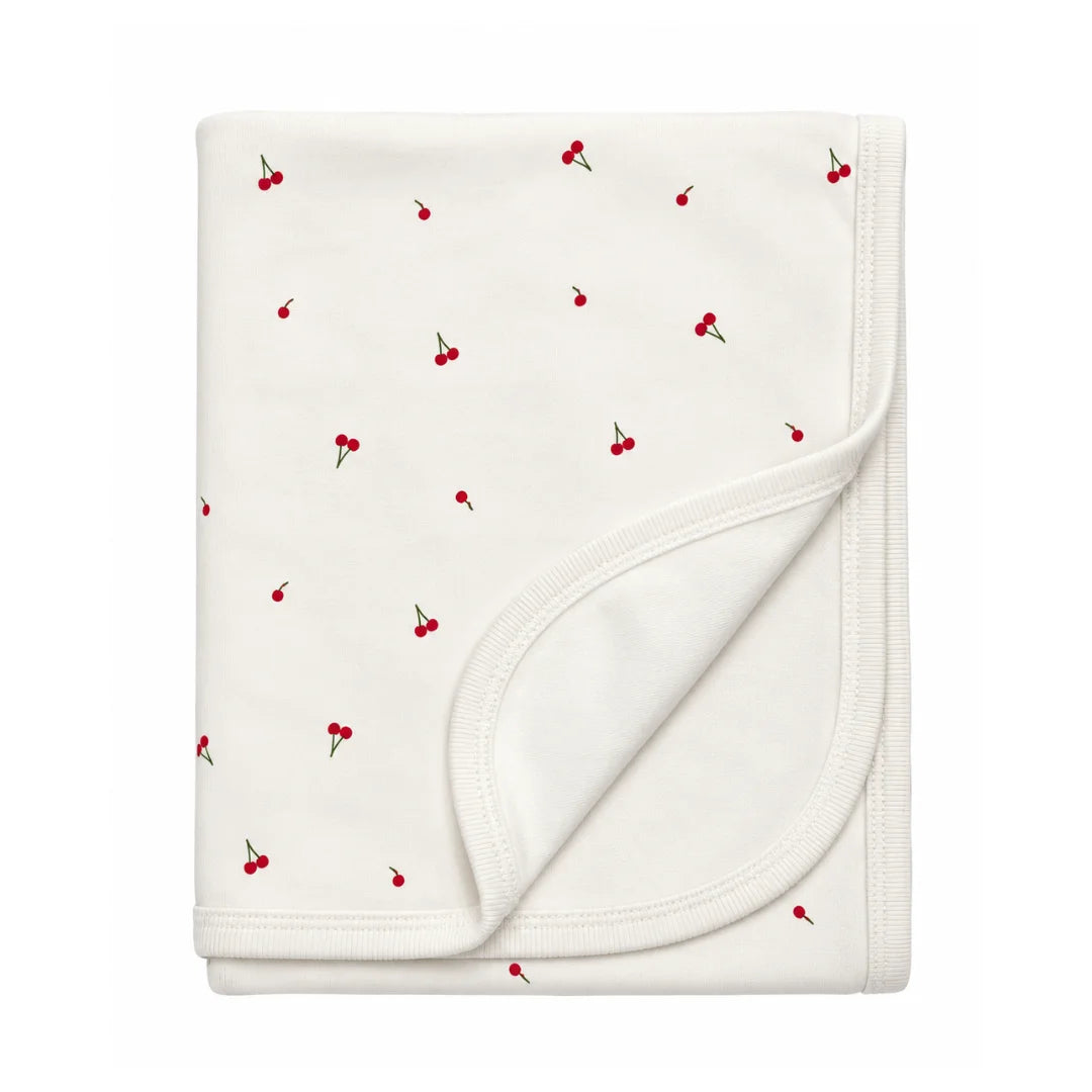 A flat-lay view of the Coton Pompom mini cherries blanket in ivory.