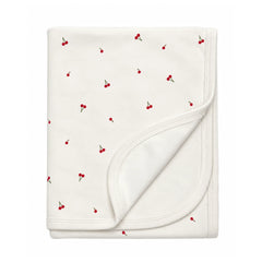A flat-lay view of the Coton Pompom mini cherries blanket in ivory.