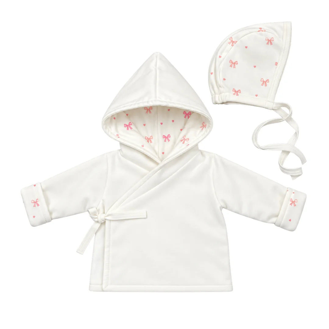 A flat-lay view of the Coton Pompom tinny luxlace jacket and bonnet set in ivory.