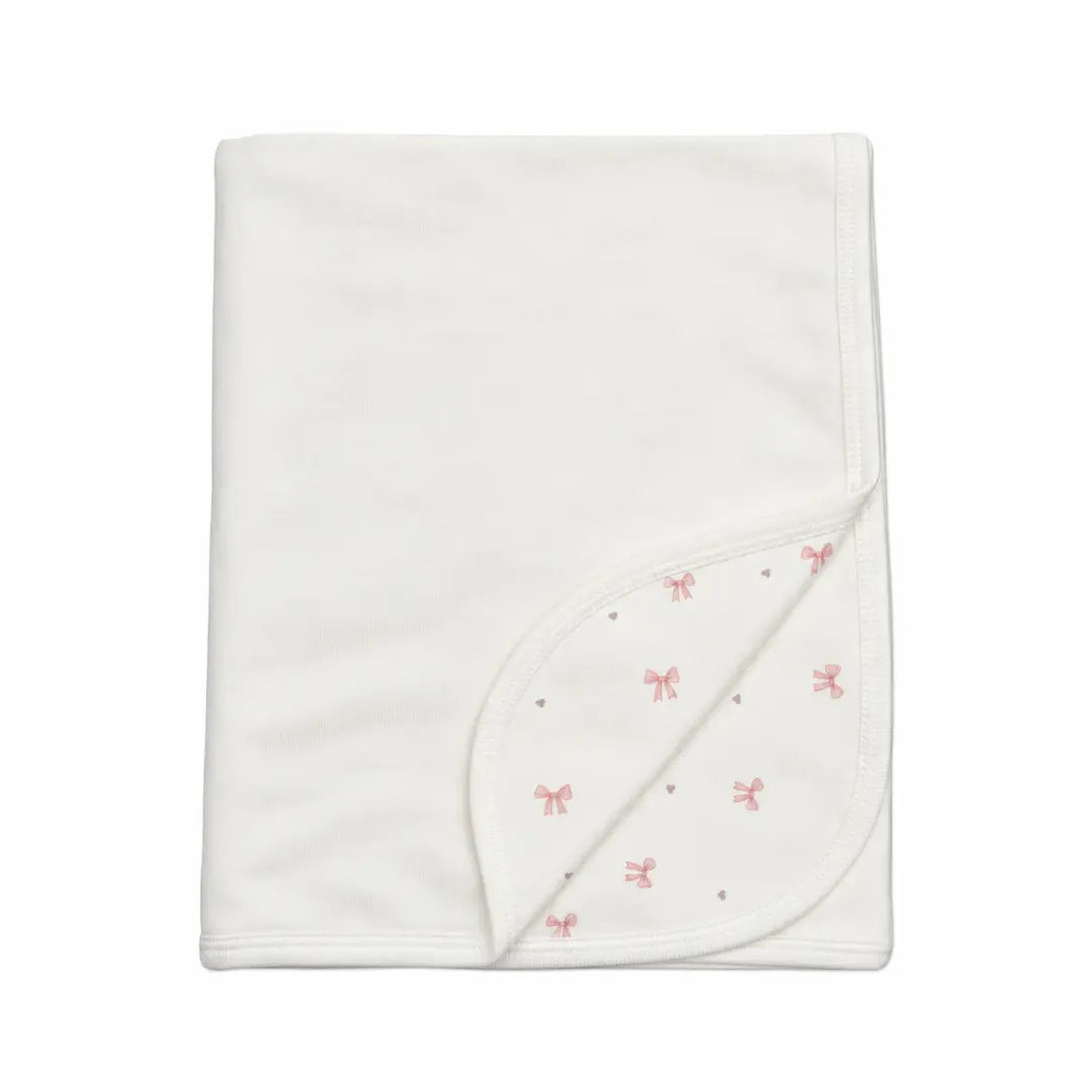 A flat-lay view of the Coton Pompom bows corduroy blanket in ivory.