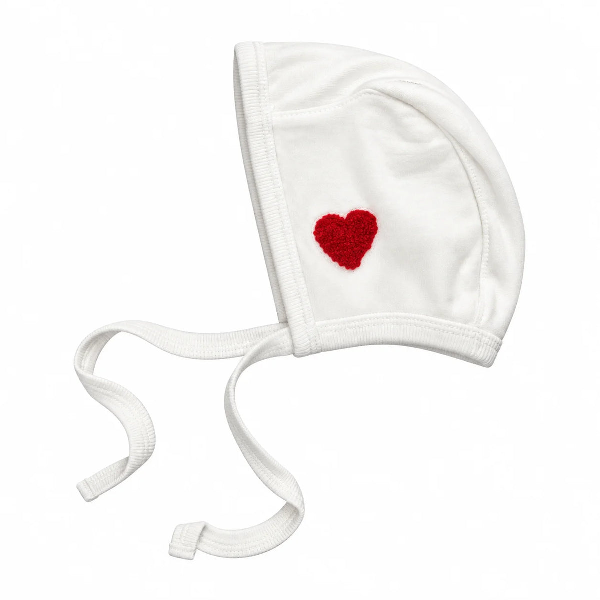 A white knit baby bonnet with white ties and a small red textured heart embroidered on the side, shown on a plain white background.