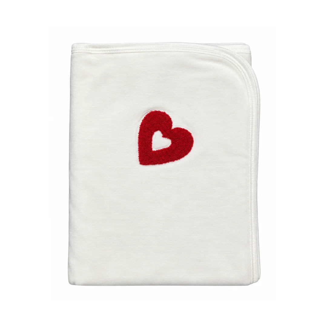 A folded white baby blanket featuring a red heart design with a white center, set against a plain white background.