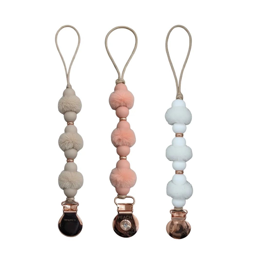 front view of the Crystal Dream pom pacifier clip in white, beige, and mauve.