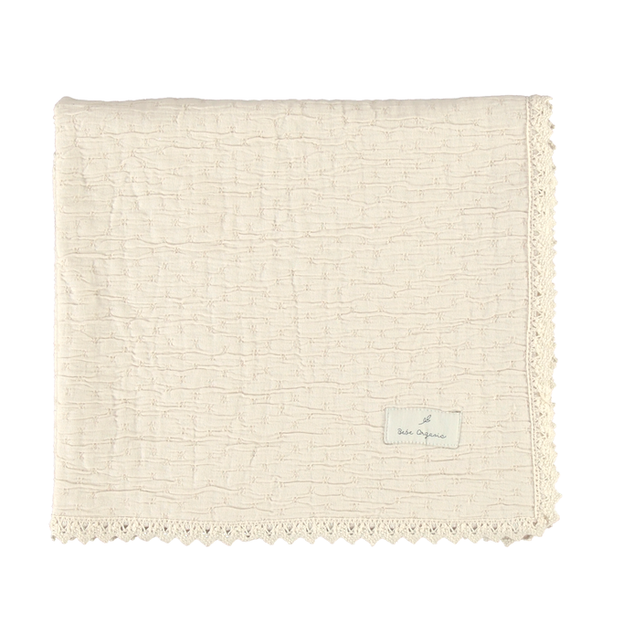 Beige textured blanket with a brand label on a white background