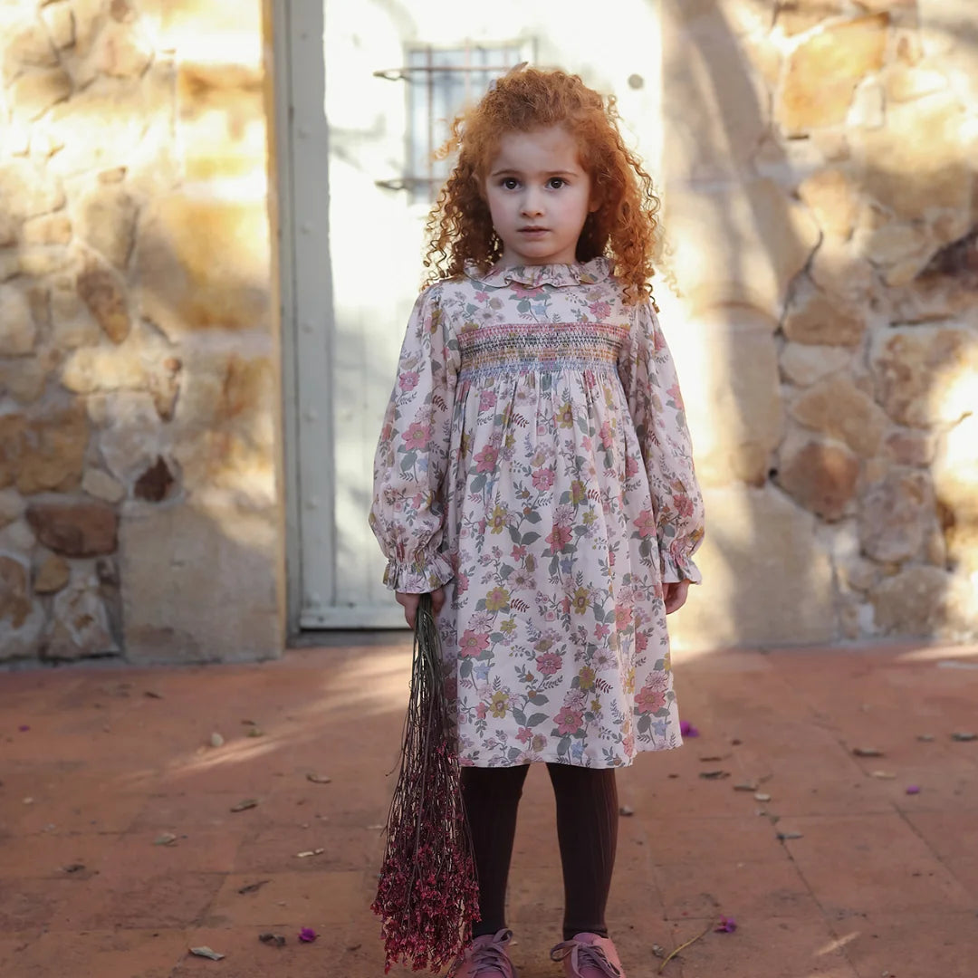 A stylish child wearing the Early Sunday floral dress during a sunlit garden outing.