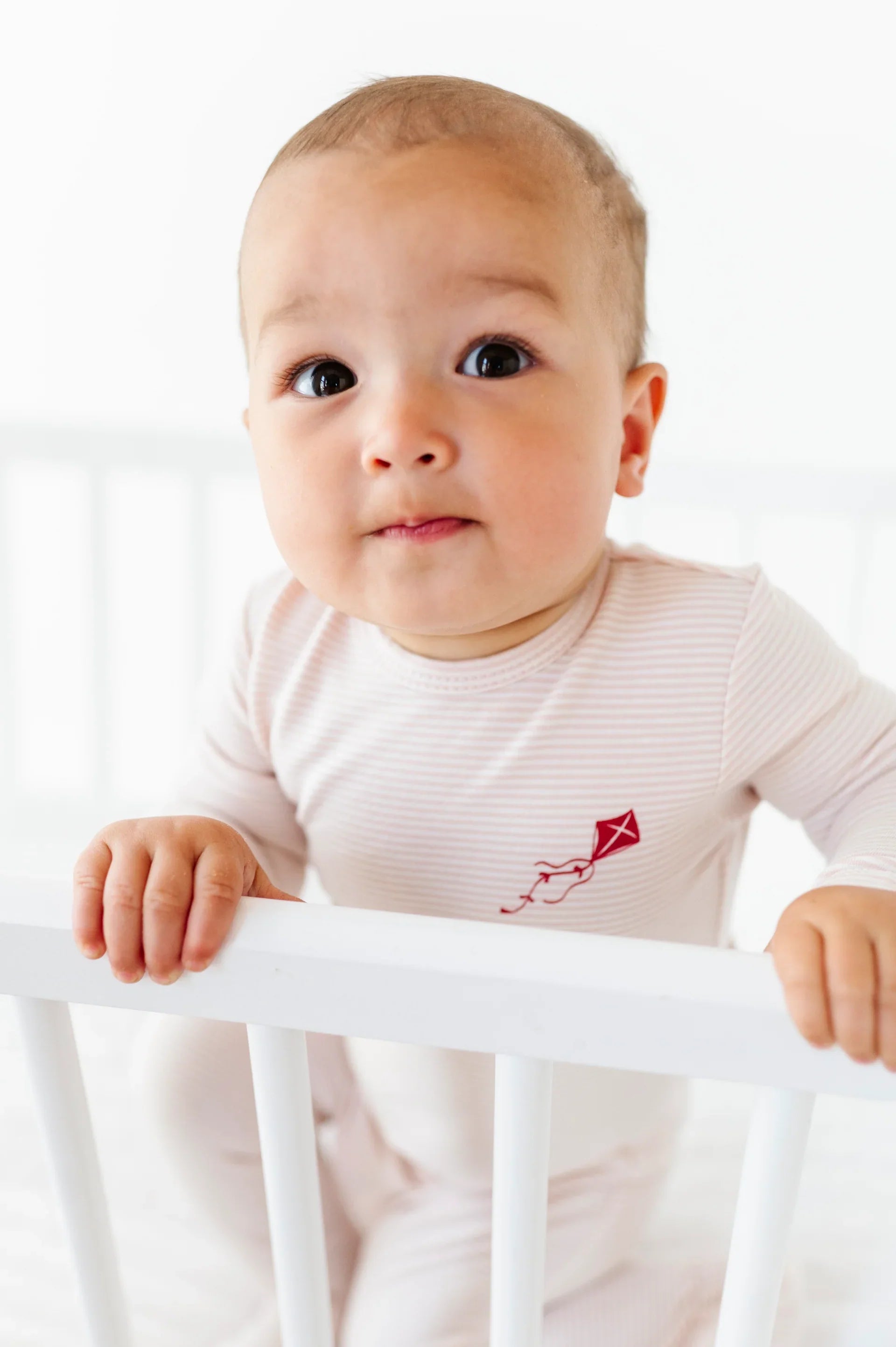 A breathtaking Ely's & Co. French Terry Footie featuring an immaculate pink striped pattern and cozy footed silhouette on baby model