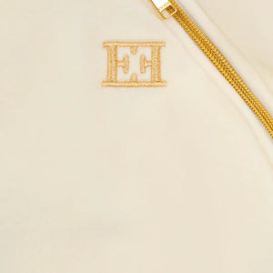 Beige clutch bag with gold chain strap and initials 'EH' on a beige background