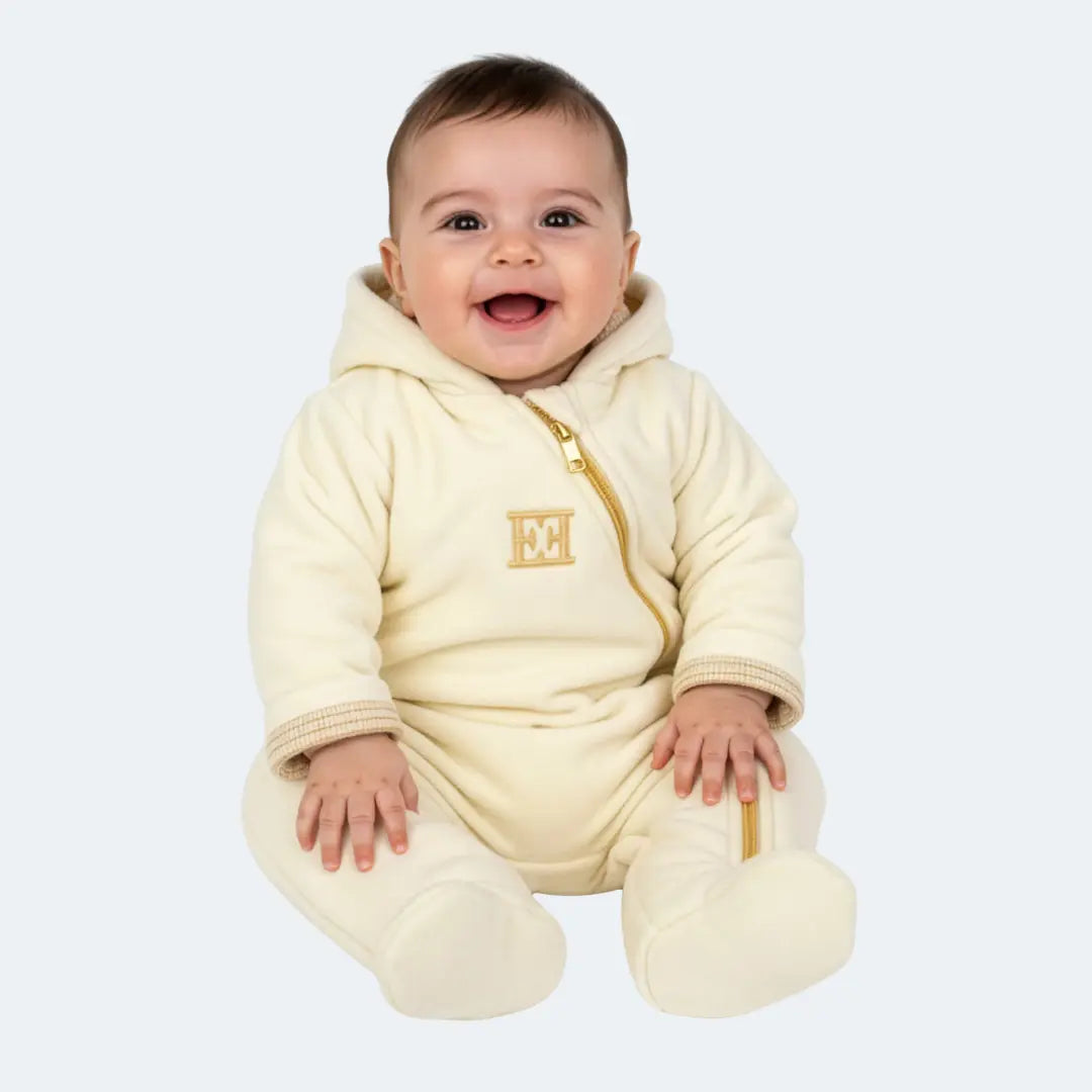 Baby wearing a cream-colored onesie with a logo on a white background