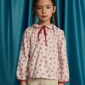 A child wearing the Gingersnaps pink floral blouse happily during an outdoor outing.