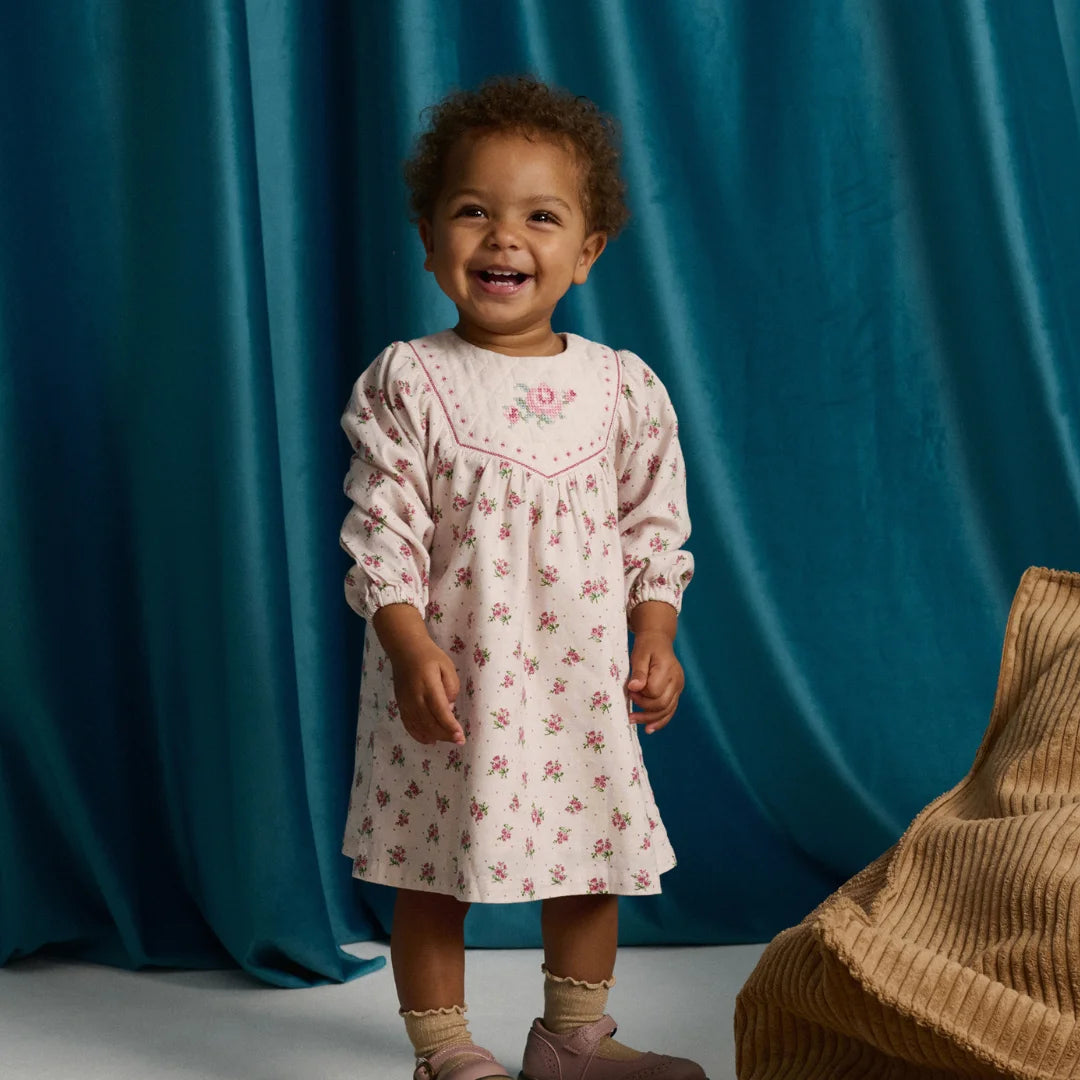 A young girl looking adorable in her pink floral Gingersnaps dress during a special outdoor gathering.