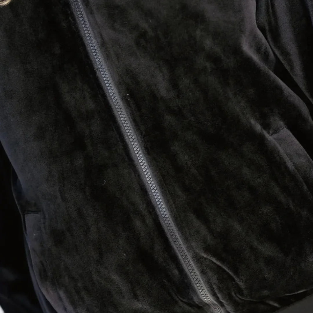 Close-up of a black velvet zip-up jacket showing the plush fabric texture and a dark zipper running diagonally across the frame.
