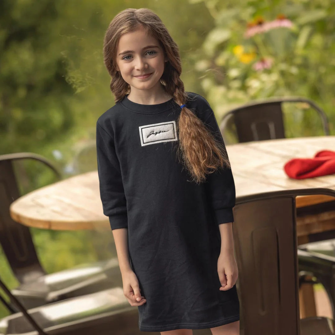 A child wearing the JayBee sherpa patch sweat dress happily during an outdoor casual outing.