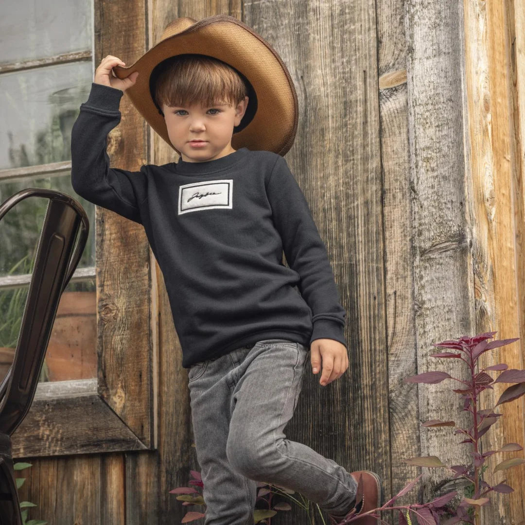 A child wearing the JayBee black sherpa patch sweatshirt happily during an outdoor casual outing.