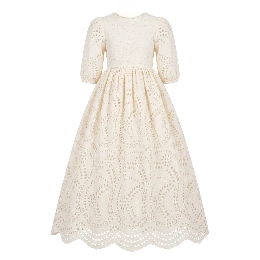 A breathtaking Jouet Broderie Gown in white, showcasing intricate eyelet embroidery and a sophisticated architectural silhouette for siblings