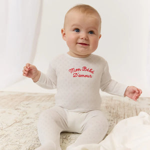 A newborn baby resting comfortably wearing the Kipp red baby footie and matching hat.