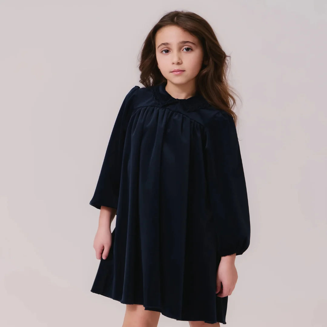 A child wearing the Kipp navy velvet dress gracefully 