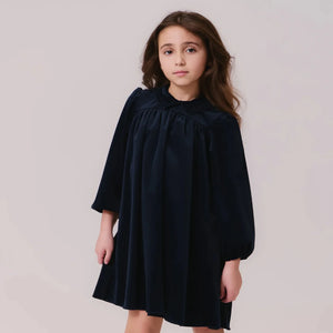 A child wearing the Kipp navy velvet dress gracefully 