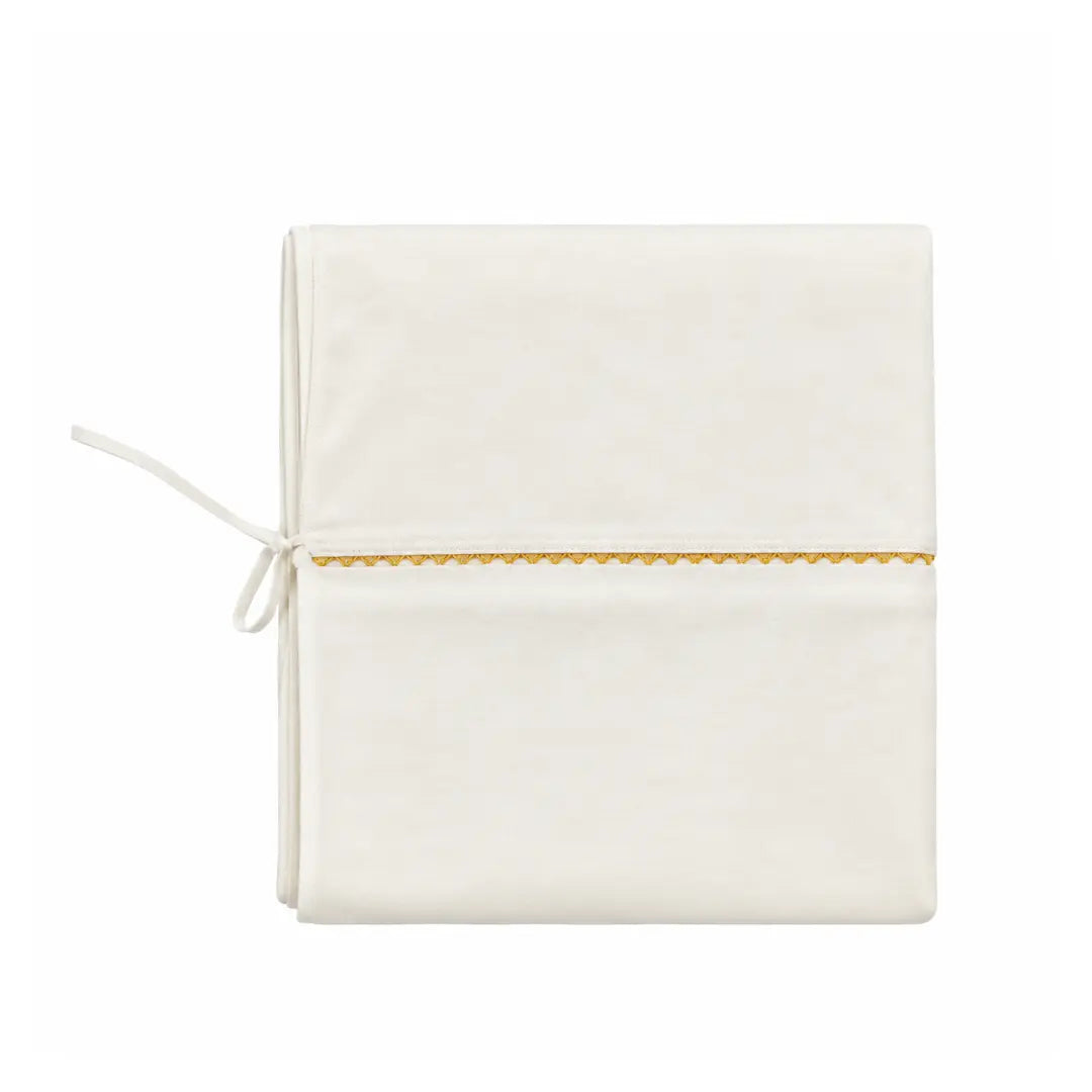 A flat-lay view of the La Mascot white and gold trim linen blanket.