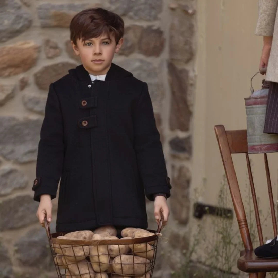 A child wearing the La Nina black wool coat comfortably during a cold winter outing.