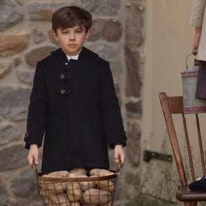 A child wearing the La Nina black wool coat comfortably during a cold winter outing.