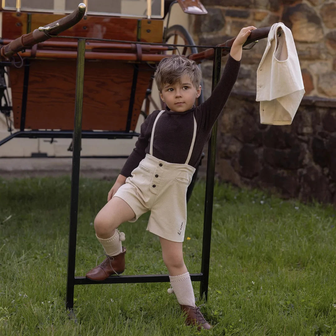 toddler wearing the La Nina cream overall set during an autumn park outing.