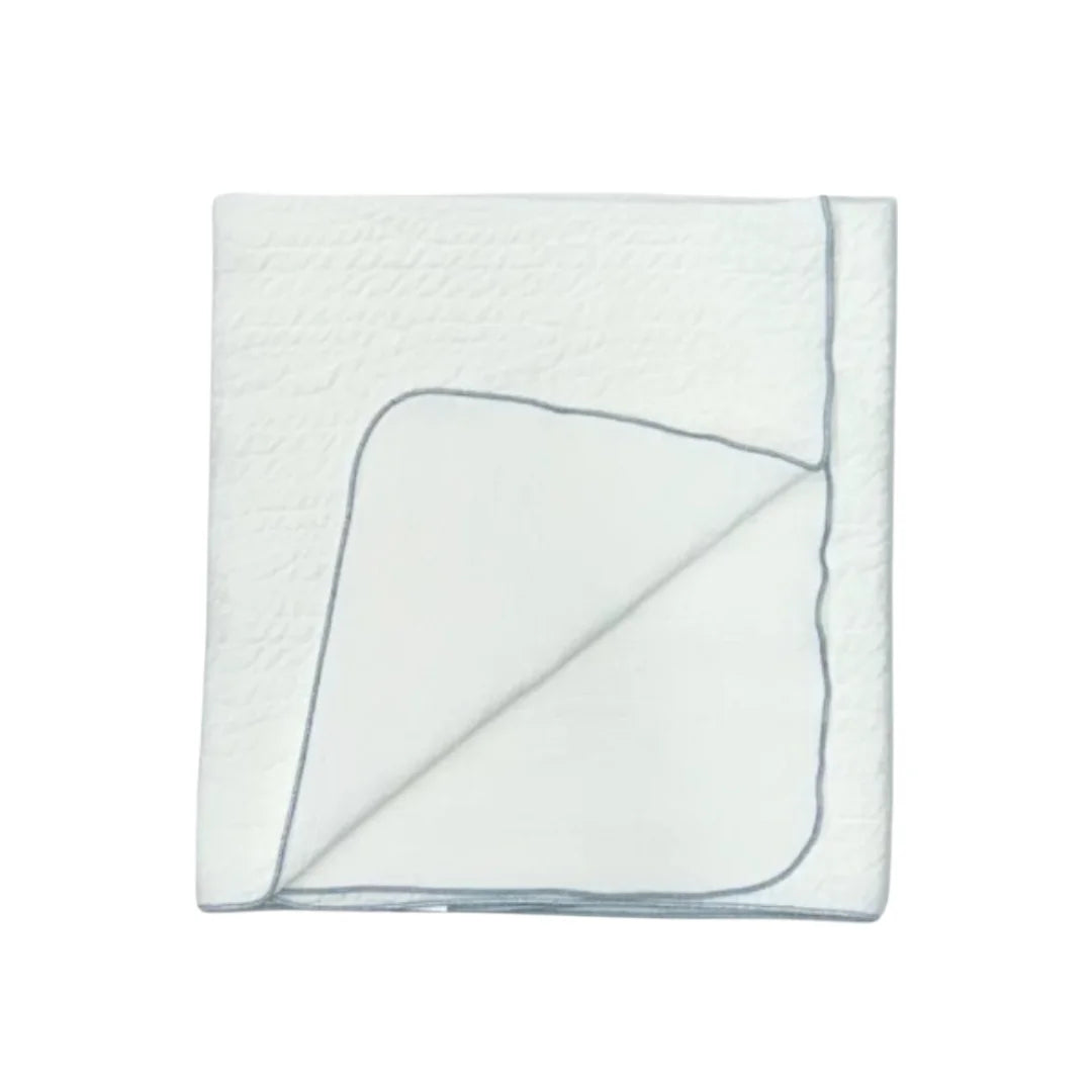 A front view of the Latte jacquard blanket in white with a blue edge.